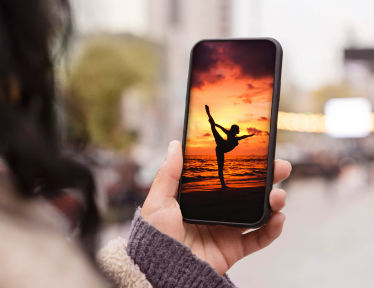 Frau hält Handy mit Bild von Yoga auf Instagram